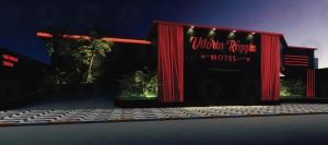 ein rotes Gebäude mit einem Schild, auf dem „Inside Return Motel“ steht in der Unterkunft Motel Vitoria Reggia in São Vicente