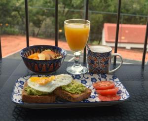 a plate of food with an egg and a glass of orange juice at Guesthouse Charis in Pretoria