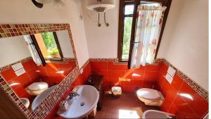 een badkamer met oranje tegels, een wastafel en een toilet. bij Appartamento Papavero Seaside and Pool in La Caduta +14 foto's