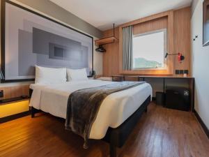 a bedroom with a large bed with a large window at ibis Navegantes Itajai in Itajaí