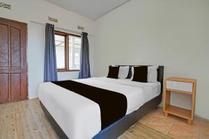a bedroom with a large white bed with blue curtains at Collection O Subang near Ciater Subang formerly Orchid Villa Ciater in Ciater