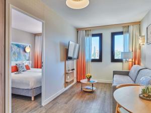 a room with a bed and a couch and a mirror at Aparthotel Adagio Aix-en-Provence Centre in Aix-en-Provence