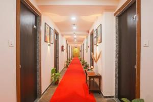 a red carpet walks down a hallway with plants at Hotel Brook View in Surat