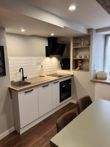 Una cocina con gabinetes blancos y un fregadero y una mesa. en L'Alcôve, en Langres 14 fotos más