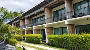 an exterior view of a building with bushes at The Nidhra Boutique Resort in Baan Tai