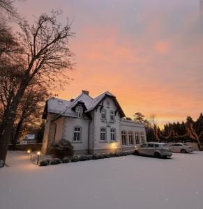 a white house with cars parked in a parking lot at Willa Legenda Hotel Adults Only in Mielno