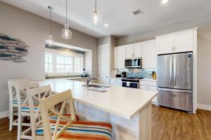 eine Küche mit weißen Schränken und eine Kücheninsel mit Stühlen in der Unterkunft The Wild Octopus at Palmilla Beach in Port Aransas