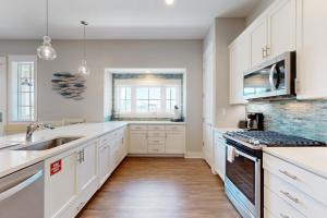 Eine Küche mit weißen Schränken, Spüle und Herd in der Unterkunft The Wild Octopus at Palmilla Beach in Port Aransas