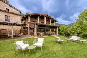an outdoor patio with chairs and tables and a building at Hotel Mas la Ferreria in La Vall de Bianya