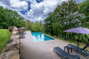a swimming pool with chairs and an umbrella at Hotel Mas la Ferreria in La Vall de Bianya