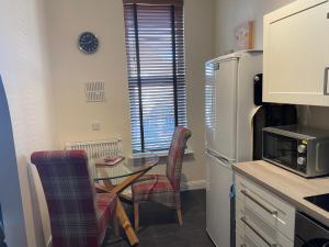 een kleine keuken met een tafel en een koelkast bij Number 10 service apartment - Danes in Southampton +2 foto's