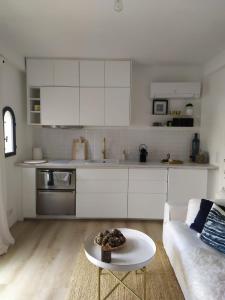 勒卡内Petite maison dans le jardin的白色的厨房配有白色的沙发和桌子