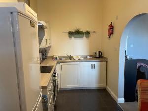 een kleine keuken met een spoelbak en een koelkast bij Number 10 service apartment - Danes in Southampton