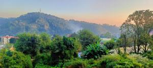 een uitzicht op een berg met bomen en gebouwen bij Mountain Breeze 2BHK with a spectacular view in Bhowāli