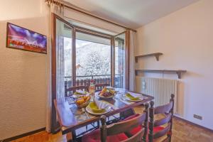 ein Esszimmer mit Tisch und Stühlen und einem Fenster in der Unterkunft Il Nido di Elda few steps from skiing - Happy Rentals in Bardonecchia