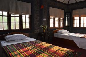 a bedroom with two beds with windows and a colorful blanket at Lei Thar Gone Guest House in Yenangyaung