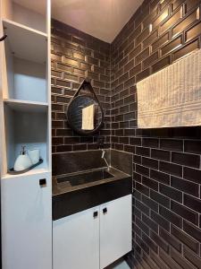 a bathroom with a sink and a brick wall at Flat completo a 50m do mar do Bessa - até 4 pessoas in João Pessoa