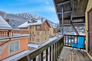 uma varanda com uma cadeira azul e montanhas cobertas de neve em Appartamento Rochebrune 200m from Ski - Happy Rentals em Claviere