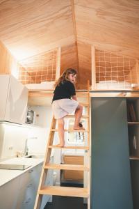a woman on a ladder in a tiny house at HolaCamp Aran Aventura in Les