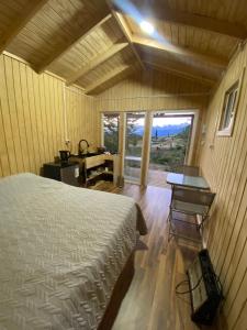 a bedroom with a bed and a desk and a window at Cabaña Huemul in Villa Cerro Castillo