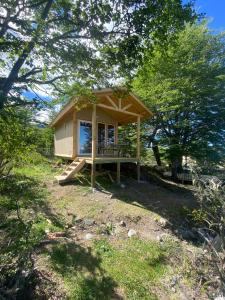 a small cabin with a porch in the woods at Cabaña Huemul in Villa Cerro Castillo