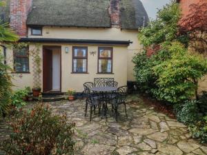 a patio with a table and chairs in front of a house at Bridge Cottage in Budleigh Salterton