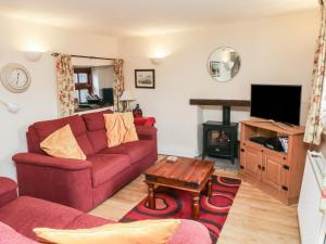 a living room with a red couch and a tv at Bridge Cottage in Budleigh Salterton
