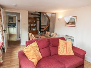 a living room with a red couch with two yellow pillows at Bridge Cottage in Budleigh Salterton