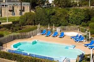 een zwembad met blauwe stoelen en een zwembad bij La Pause Iodée - 100m de la plage in Bénodet