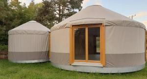 Zwei Jurtenhäuser stehen im Gras. in der Unterkunft Jurajskie Jurty in Golczowice