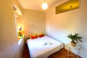 una piccola camera da letto con un letto bianco con cuscini arancioni di L Ambrosien, un nid douillet a Saint-Ambroix