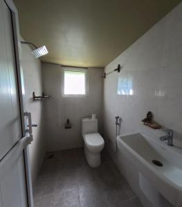 Un baño blanco con inodoro y lavabo. en Bulbul Farm Retreat, en Tānsing 49 fotos más