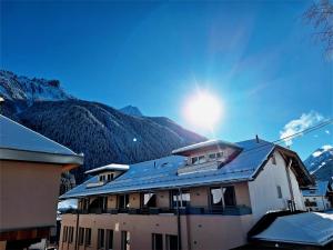 Un edificio con el sol en el cielo y montañas. en Dorf.Apart, en Neustift im Stubaital