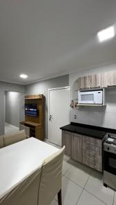 a kitchen with a white table and a microwave at Apartamento Centro Capão da Canoa 2 Quadras do mar in Capão da Canoa