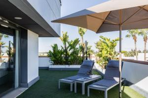 um pátio com duas cadeiras e um guarda-sol em Sevilla Green Suites em Alcalá de Guadaira