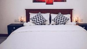 MaskeliyaChanuka Rest的卧室配有白色的床和黑白色枕头