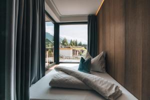 Cama con almohadas en habitación con ventana en Hotel Nassereinerhof, en Sankt Anton am Arlberg