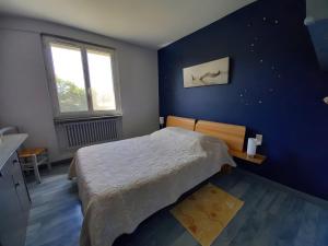 une chambre avec un lit et un mur bleu dans l'établissement Gîte Harmony, à Châteauneuf-du-Rhône