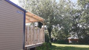 a wooden pergola on the side of a house at Mobil-home neuf - Au bleu du ciel in Plouhinec +2 photos