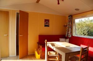 a dining room with a table and a window at Mobil-home Les volets rouges in Plouhinec