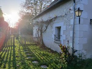 ein altes weißes Backsteingebäude mit einem Fenster und einer Lampe in der Unterkunft L'Atout de France in Fléré-la-Rivière