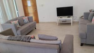 ein Wohnzimmer mit Sofas und einem Flachbildfernseher in der Unterkunft Paradise Found 3Bedroom Apartment with Pool in Las Terrenas