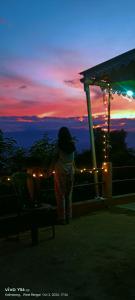 a woman standing next to a chair at sunset at ABM Homestay in Kalimpong