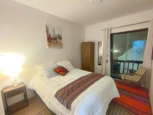 a bedroom with a bed and a table and a window at Maruri Valentino apartment in Cusco