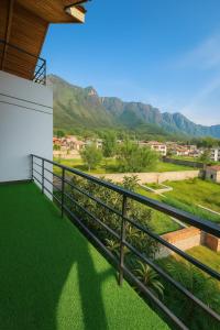 un balcón con césped verde y montañas al fondo en The Holiday Home, en Srinagar