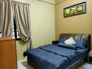 a bedroom with a bed with blue sheets and a window at HANNI HomeStay in Sibu