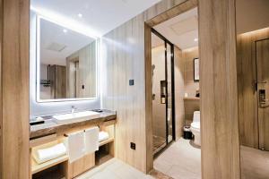 a bathroom with a sink and a toilet and a mirror at Qingdao Likelai Garden Hotel in Qingdao