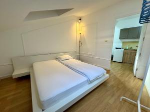 a white bed in a room with a kitchen at Riseup apartman in Niš +10 photos