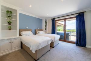 two beds in a bedroom with a large window at Lakeside in Compton Martin