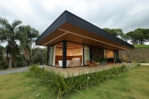 a small house with a black roof in a field at Casa de Campo - Valle Paixão in Campo Largo